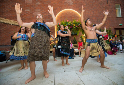 Maori performers in traditional dress energetically lead a Haka team building session, inspiring participants with chants and powerful movements.