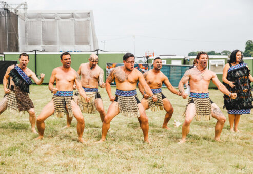 Team building participants performing a traditional Haka dance, led by Maori facilitators in traditional attire.