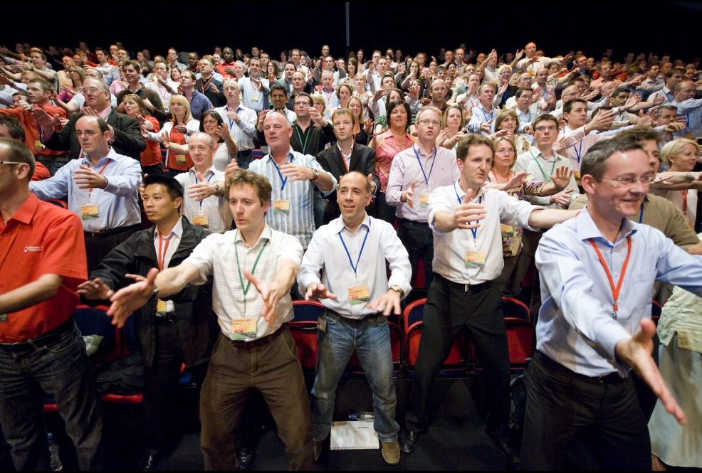 Large group of participants standing together in unison, performing synchronized Haka dance moves during a team building event.