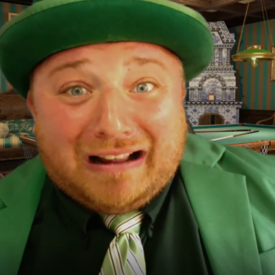 A man wearing a bright green suit, green tie, and matching green hat is seen in the foreground with an exaggerated, nervous expression on his face. The man’s expression and vivid outfit create a humorous and lively atmosphere. He's role-playing in a murder mystery team building event. thumbnail
