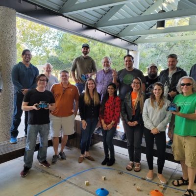 A group of participants pose together after a successful outdoor team building event, proudly holding their completed robots. thumbnail