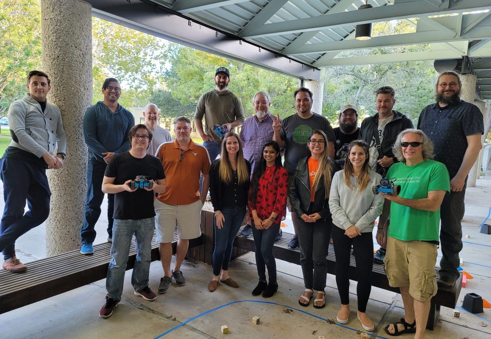 A group of participants pose together after a successful outdoor team building event, proudly holding their completed robots.