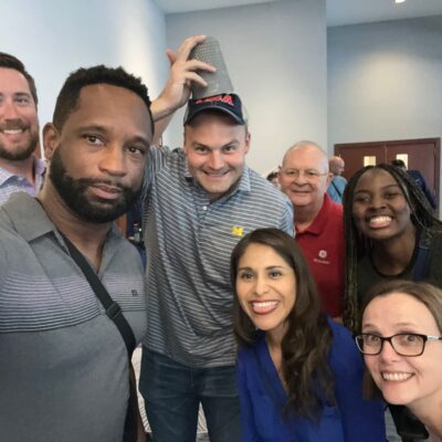 A group of participants posing for a fun selfie during a Team-opoly scavenger hunt team building event. thumbnail