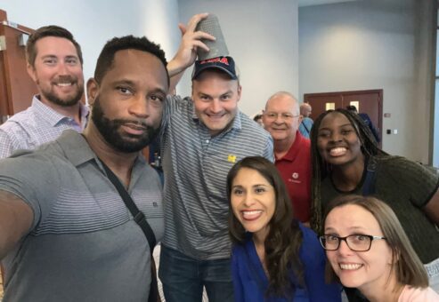A group of participants posing for a fun selfie during a Team-opoly scavenger hunt team building event.