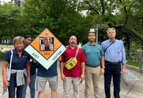 Team posing with a Monopoly-style 'In Jail' prop during a Team-opoly scavenger hunt team building event.