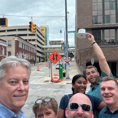 Team posing with a white cup in the air during a scavenger hunt at a team building event. thumbnail
