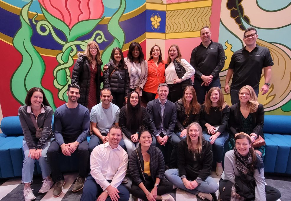 Team photo in front of a vibrant mural during a Mystery Bus team building event, capturing a moment of camaraderie and excitement.