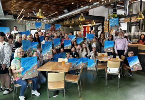 Group showcasing their ocean-inspired paintings after a creative session during a Mystery Bus team building event.