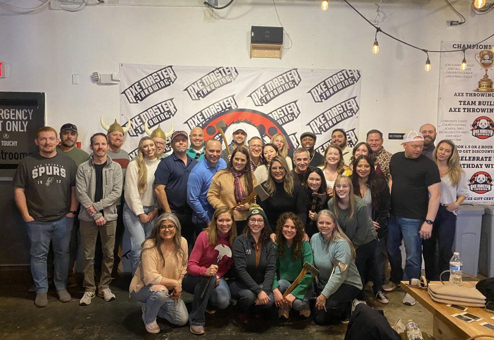 Team posing with axes after a competitive and fun axe-throwing session during a Mystery Bus team building event.