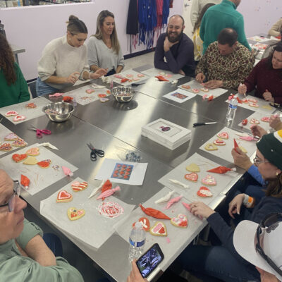 Team decorating heart-shaped cookies during a creative baking stop on the Mystery Bus team building adventure. thumbnail