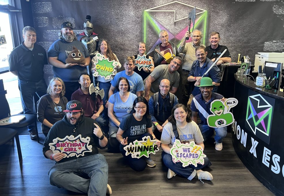 Group celebrating success after completing an escape room challenge during their Mystery Bus team building event.