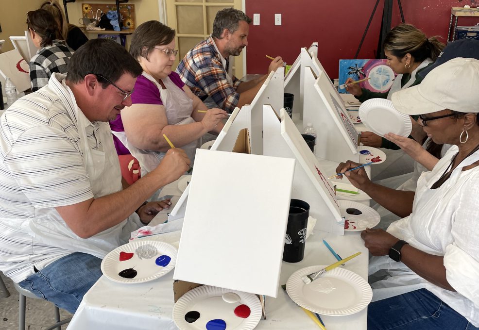 Participants in The Mystery Bus team building event paint canvases, engaging in a creative and collaborative experience.