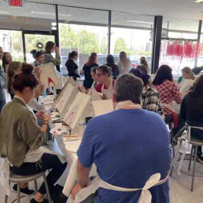 Team members participate in a painting activity during The Mystery Bus team building event, focusing on creativity and collaboration. thumbnail