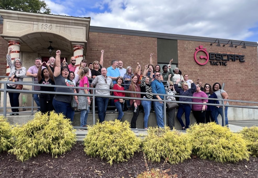 Team celebrating success after completing an escape room challenge during their Mystery Bus team building event, showcasing teamwork and problem-solving skills.