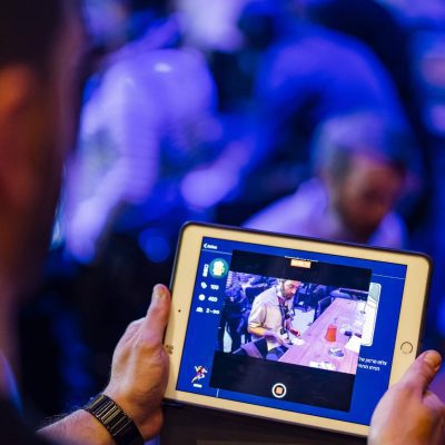 A participant engages with a tablet during a team building event, capturing moments of the activity in a lively, high-tech environment. thumbnail