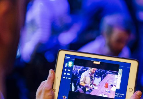A participant engages with a tablet during a team building event, capturing moments of the activity in a lively, high-tech environment.
