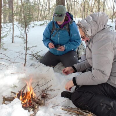 Two people on team building outing starting a campfire