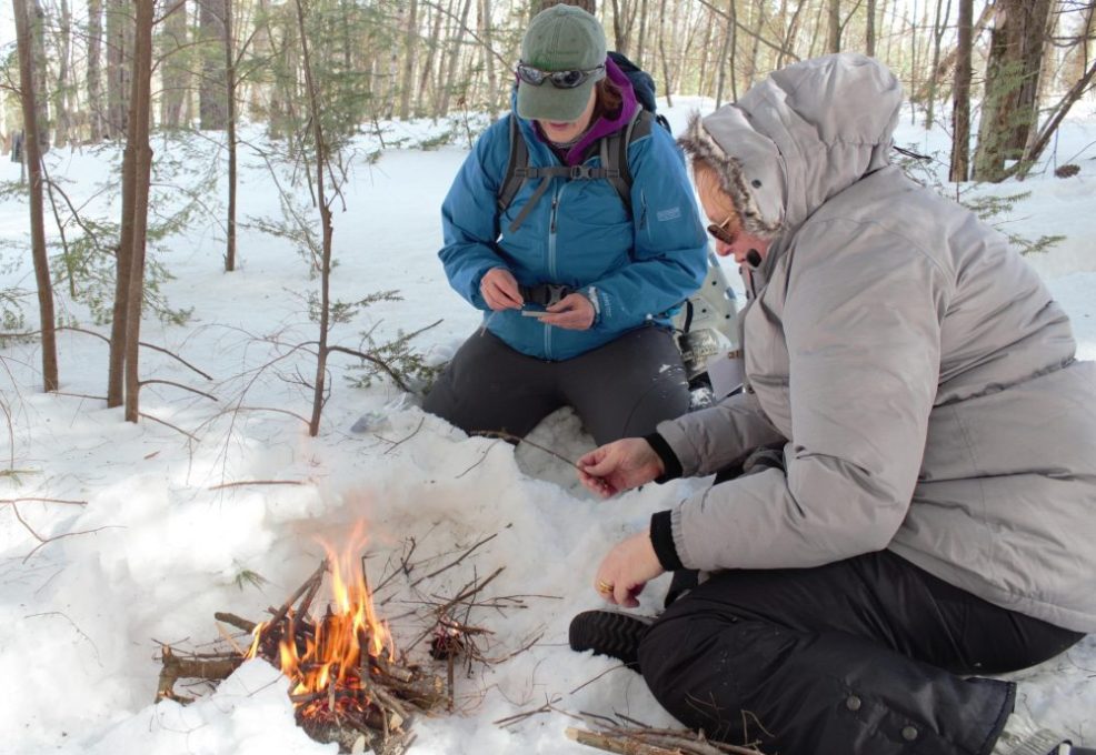 Two people on team building outing starting a campfire