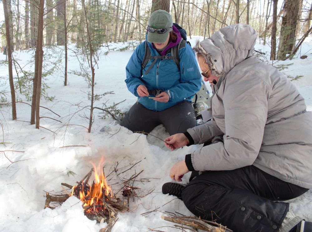 Two people on team building outing starting a campfire