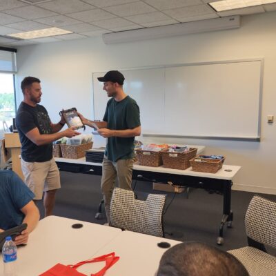 Team members collaborate and exchange items during the Hopefull Handbags Global team building event, packing essential items into handbags for survivors of domestic abuse. thumbnail