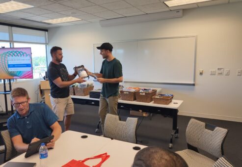 Team members collaborate and exchange items during the Hopefull Handbags Global team building event, packing essential items into handbags for survivors of domestic abuse.