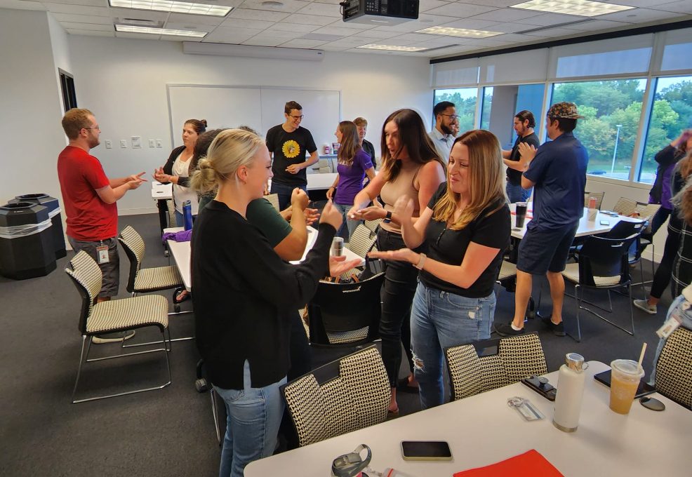 Team members engaged in an interactive Hopefull Handbags Global team building event, preparing essential care items to be packed into handbags for domestic abuse survivors.