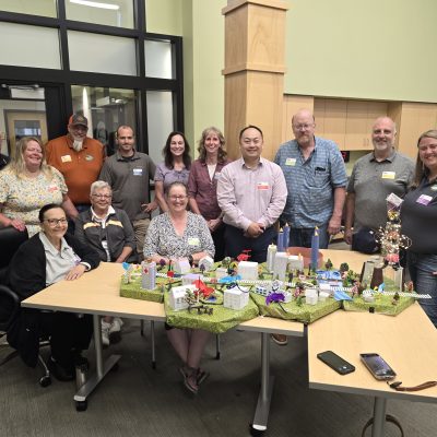 Group photo of participants proudly showcasing their completed miniature city model at the City Build team building event. thumbnail
