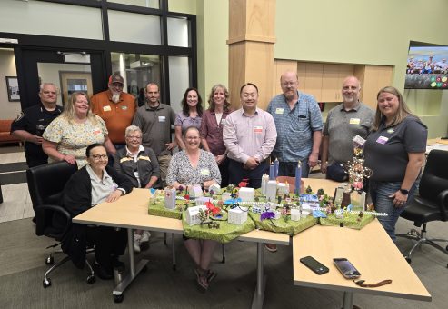 Group photo of participants proudly showcasing their completed miniature city model at the City Build team building event.
