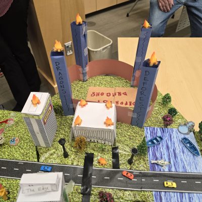Creative city model with labeled towers, roads, waterways, and miniature vehicles, showcasing teamwork from the City Build team building event. thumbnail