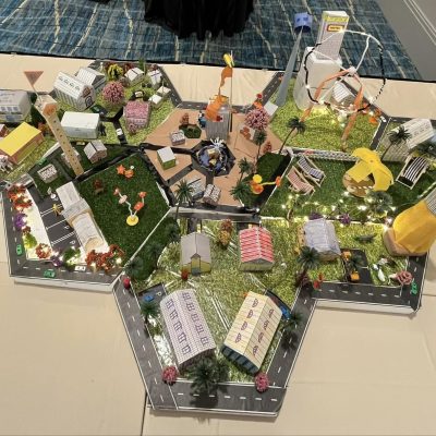 Overhead view of a completed City Build project featuring a connected miniature city with buildings, roads, and parks, created during a collaborative team building activity. thumbnail