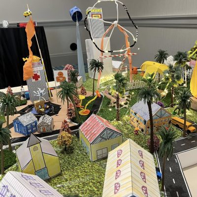 Colorful miniature city layout with houses, trees, roads, and decorative lights, created during a City Build team building activity. thumbnail