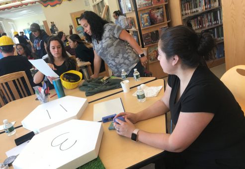 Participants working together at a City Build team building event, preparing materials and brainstorming plans for their collaborative city project.