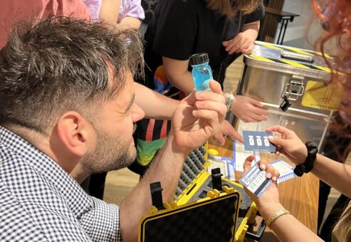 Team members collaborating during the 'Atmosphere' team building event, examining a vial as part of a puzzle.