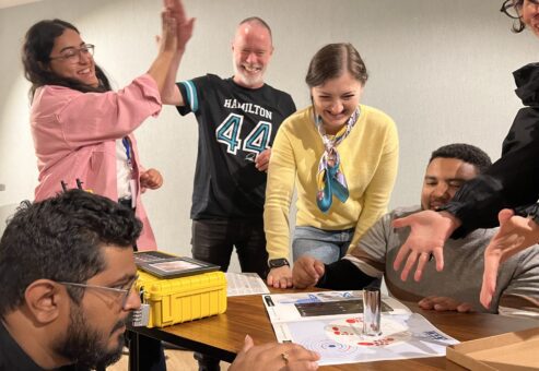 Team celebrating a breakthrough while solving puzzles during the 'Atmosphere' team building event.