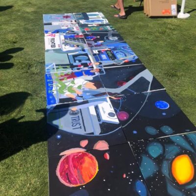 A completed space-themed mural with vibrant images of planets, astronauts, and the word 