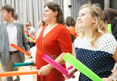 Team members actively participating in Boom Time, a musical team building activity. They collaborate with colorful Boomwhackers to create music, fostering teamwork, energy, and communication.