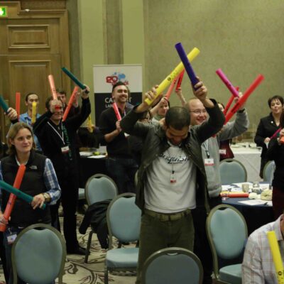 Group of participants enthusiastically playing colorful Boomwhackers in unison during a dynamic team building activity, fostering collaboration and rhythm. thumbnail