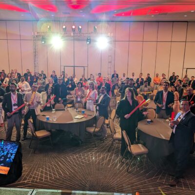 Conference attendees participating in a musical team building activity, holding colorful Boomwhackers and following along with rhythms on a large screen. thumbnail