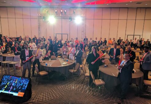 Conference attendees participating in a musical team building activity, holding colorful Boomwhackers and following along with rhythms on a large screen.