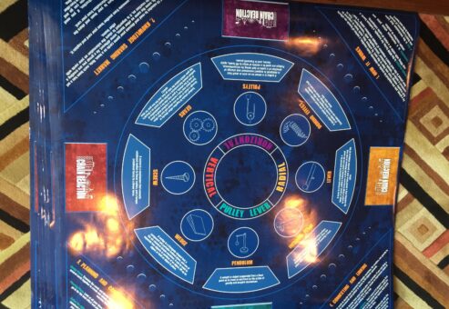 Close-up of a game board illustrating mechanics like pulleys, levers, and gears, used as part of a chain reaction team building activity.