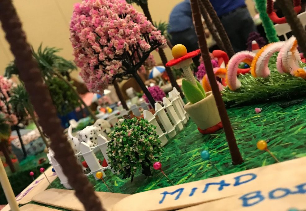 Close-up of a creative miniature city build with vibrant greenery, pink trees, and decorative pathways during a City Build team building event.
