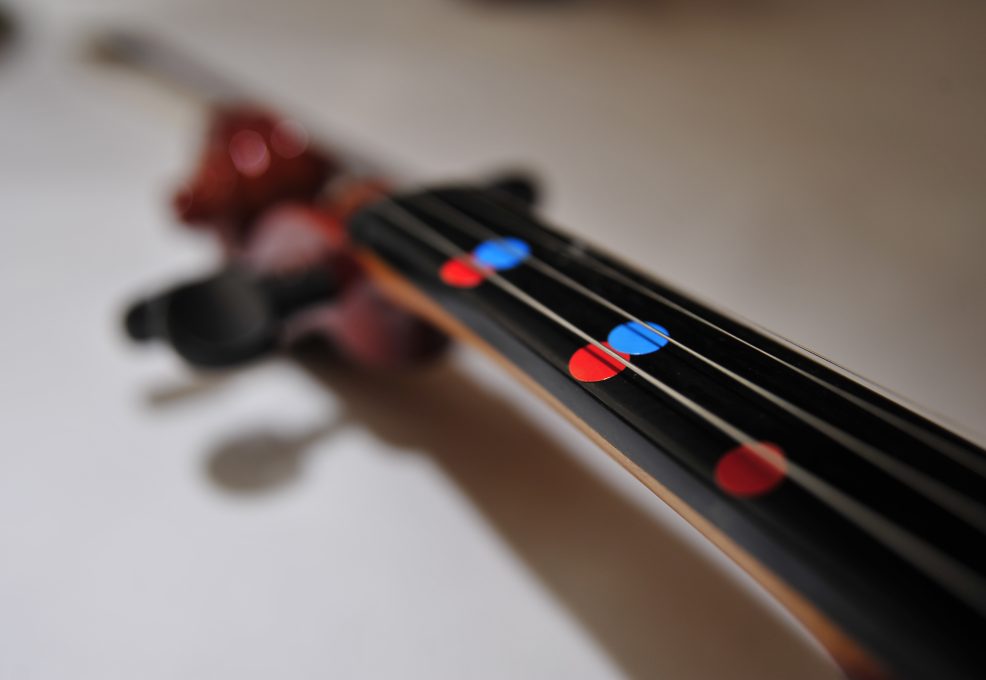Close-up of a violin’s fingerboard with colorful markers to help participants learn notes quickly during the Crescendo team building event.