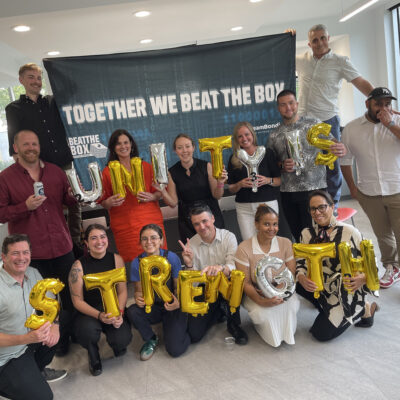 Team proudly displaying 'Unity is Strength' balloons after completing the Beat the Box team building event, celebrating their collaboration and shared achievement. thumbnail
