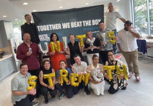 Team proudly displaying 'Unity is Strength' balloons after completing the Beat the Box team building event, celebrating their collaboration and shared achievement.