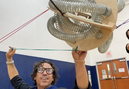 A participant holding a complex structure as part of the Integrity team building event, demonstrating teamwork and balance in a physical challenge.