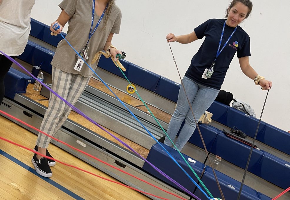 Participants working together in the Integrity team building event, using ropes to carefully balance wooden blocks as part of a collaboration challenge.
