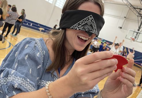 A participant blindfolded and smiling while completing a challenge in the Integrity team building event, focused on teamwork and communication.