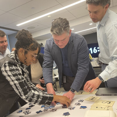 Focused participants work together on a challenging puzzle during a Beat The Box team building event, racing against the clock to achieve success. thumbnail