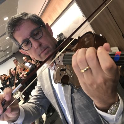 Focused participant practices playing the violin during the Crescendo team building event, showcasing teamwork. thumbnail