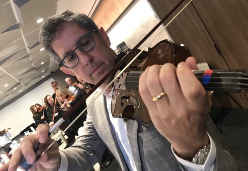 Focused participant practices playing the violin during the Crescendo team building event, showcasing teamwork.